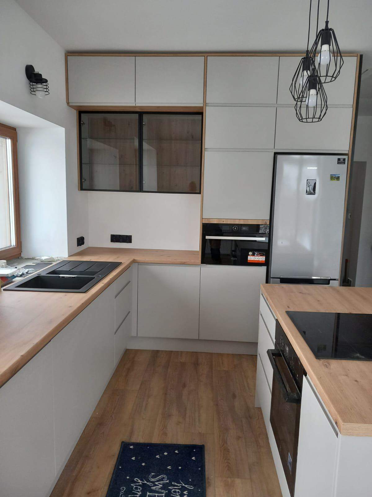 biała kuchnia  z drewnianym blatem i wyspą wykonane na wymiar 