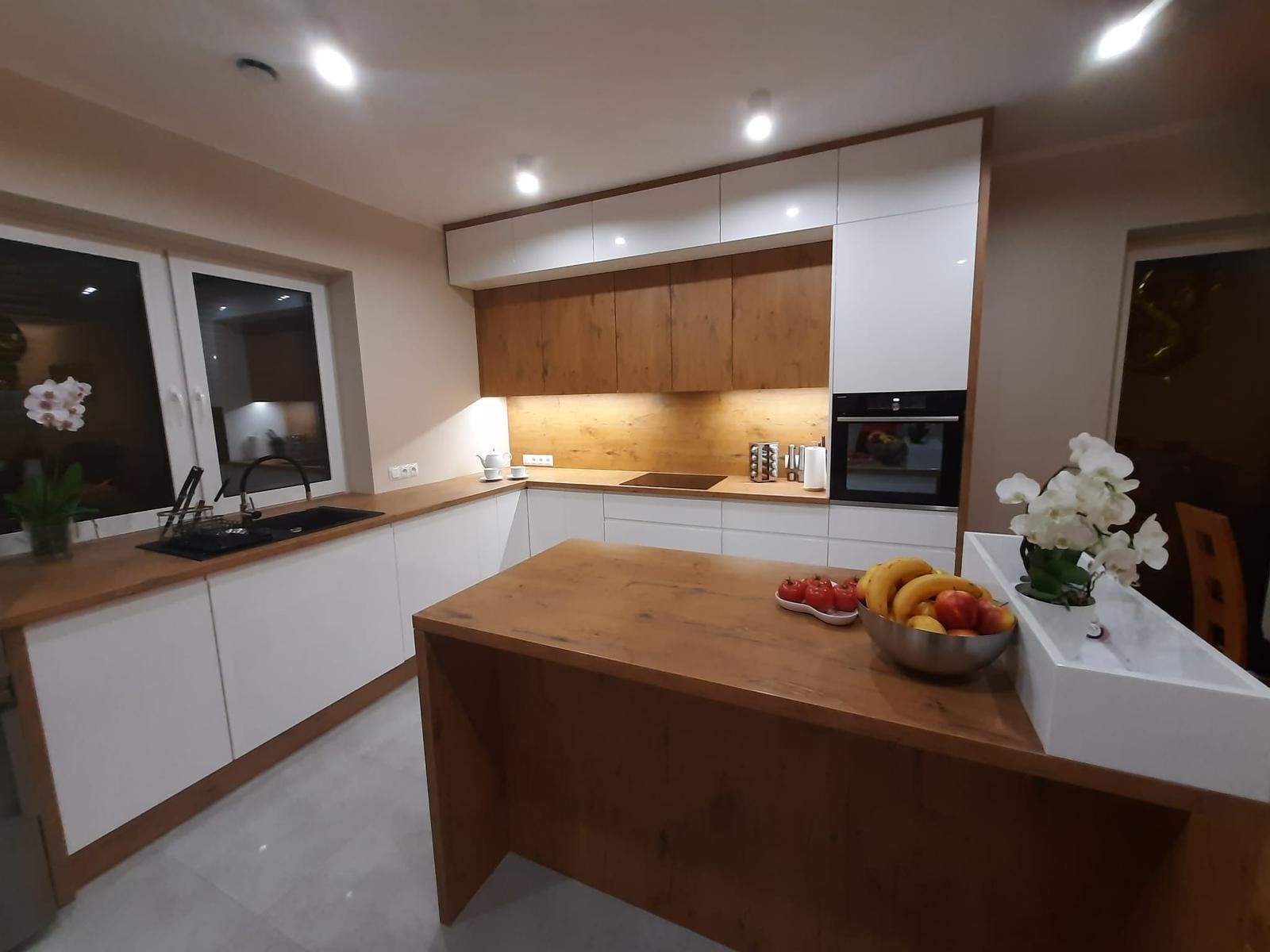 Biała kuchnia lakierowana z frezowanym uchwytem oraz drewnianym wykończeniem  na wymiar 