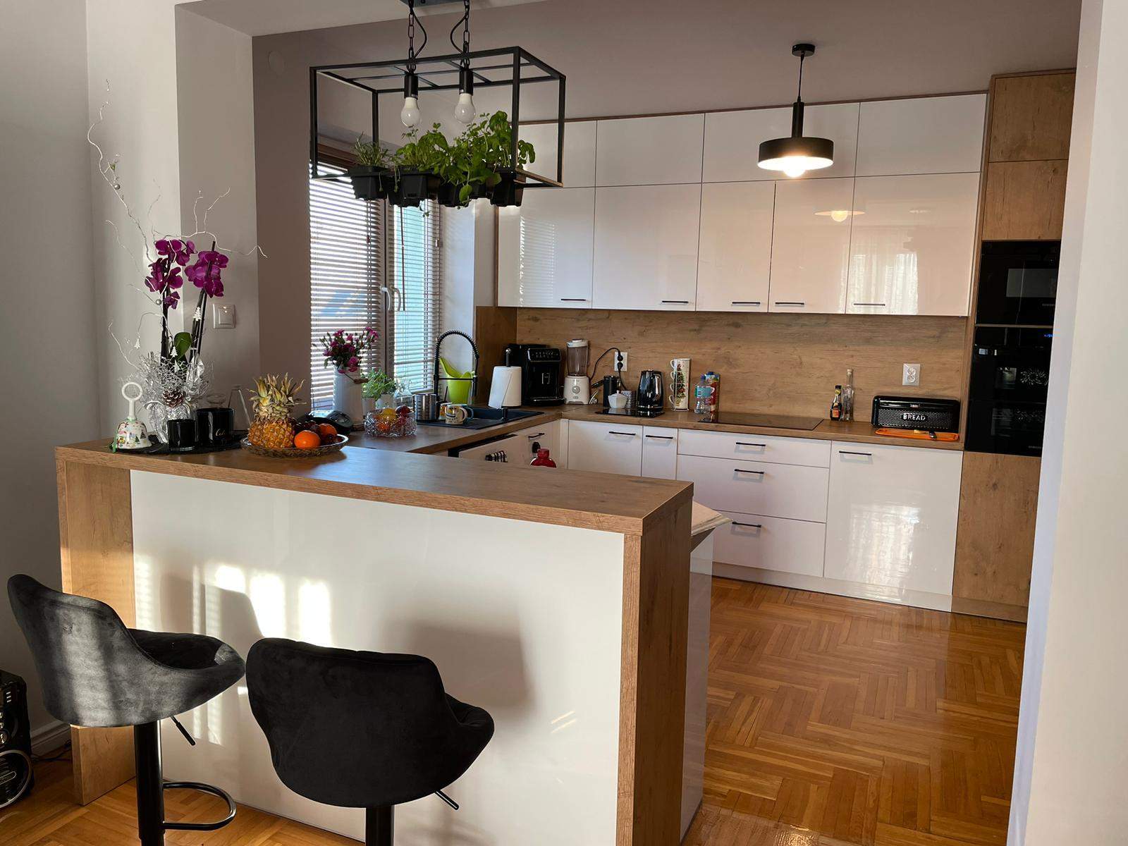 biała akrylowa kuchnia na wymiar z drewnianym wykończeniem  i wyspą śniadaniową 